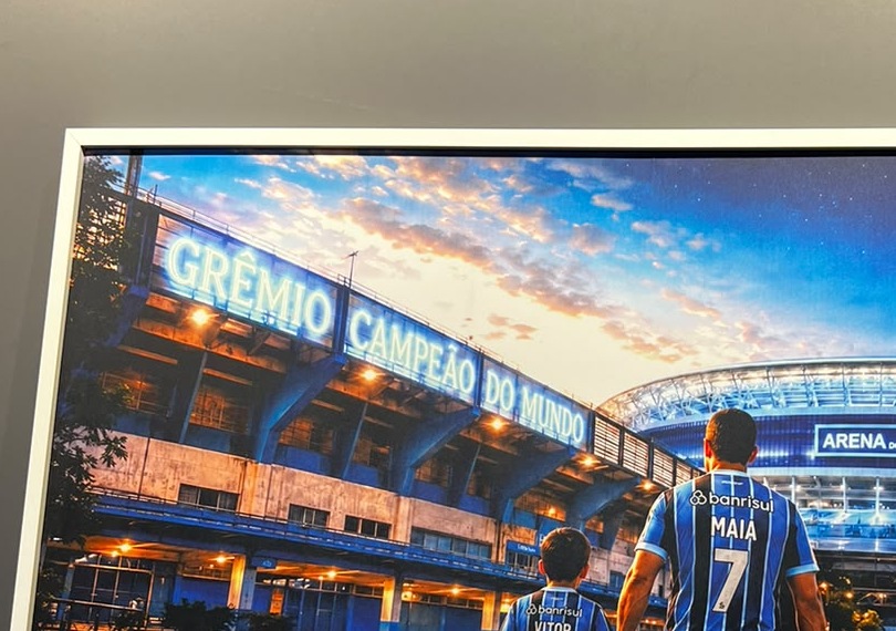 Canto do quadro em close: moldura branca, vidro e a impressão do letreiro Grêmio Campeão do Mundo